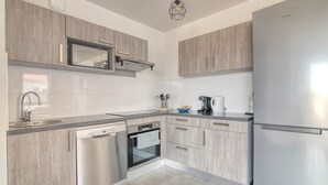 A modern kitchen with wood cabinetry, stainless steel appliances, and a tiled backsplash. - The Cocoon - Appt avec terrasse, 20mn de Toulouse (Castelginest)