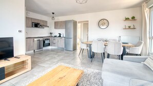 A modern living room with a TV, sofa, coffee table, and dining area with chairs and a table. - The Cocoon - Appt avec terrasse, 20mn de Toulouse (Castelginest)