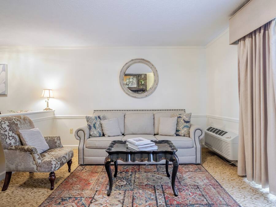 Een woonkamer met een bank, fauteuil, salontafel en een kamerkleed met een patroon.