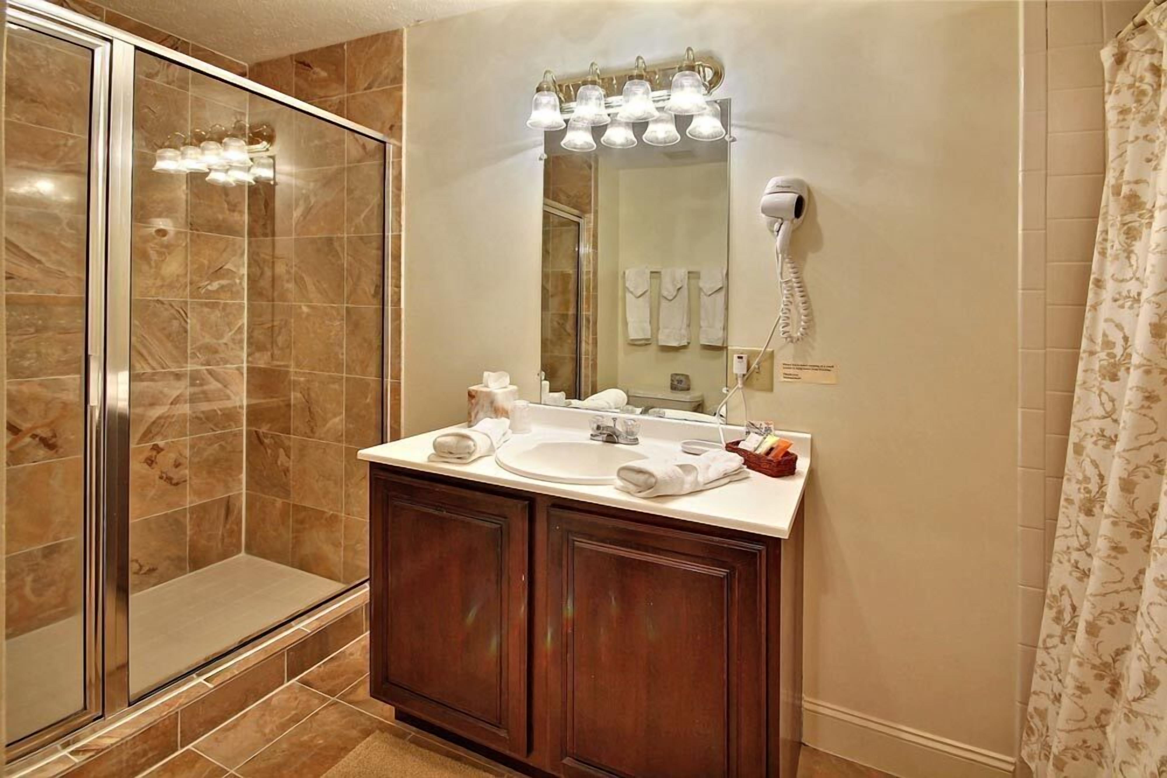 A bathroom with a shower, a sink, and a mirror.