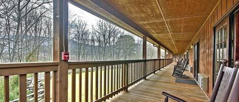 Une terrasse en bois couverte, dotée de bancs, qui offre une vue sur une zone boisée.