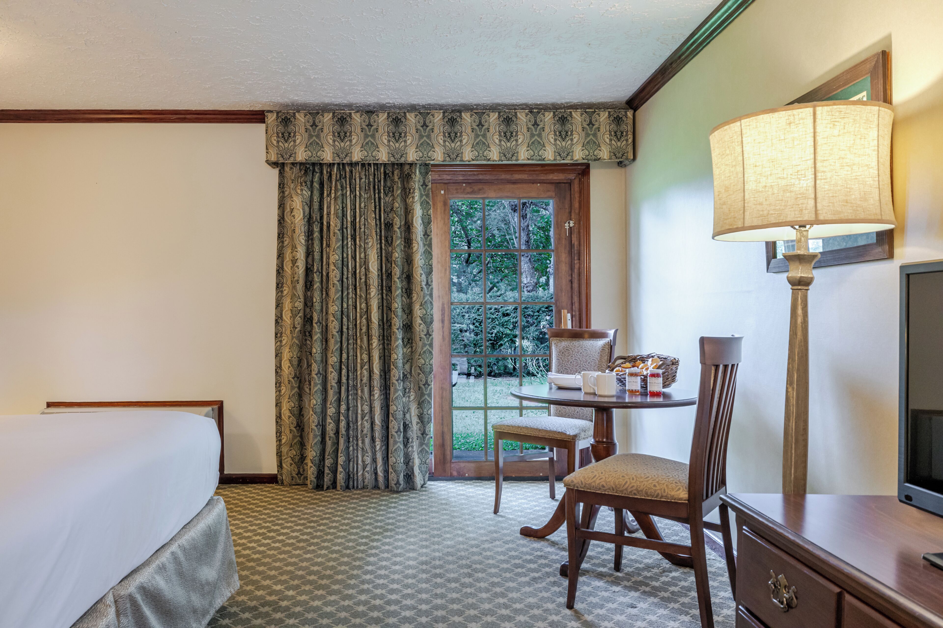 Une chambre d’hôtel avec un lit, un bureau doté d’une lampe, une chaise et une vue sur l’extérieur par une fenêtre.