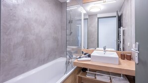 Een moderne badkamer met een grote spiegel, een wit wastafelmeubel en een douche met glazen wanden.