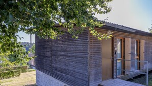 Een klein, modern vakantiehuisje met een houten gevel, een klein terras en een deur naar binnen.