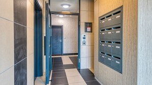 Un espace moderne avec ascenseurs, un comptoir d’accueil, des boîtes aux lettres et une porte donnant sur une autre pièce.