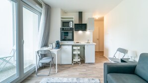 Une cuisine moderne équipée d’un four à micro-ondes, d’un four et d’un évier intégrés, un coin repas avec une table et des chaises, et un canapé.