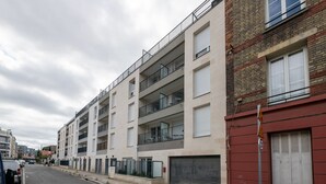 A multi-story residential building with balconies, a garage, and a street view. - Moulin à Vent A14 - Appt pour 4 avec balcon (Bondy)