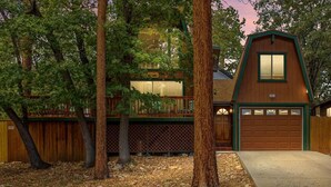 A wooden cabin with a garage, surrounded by trees.
