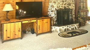 A wooden interior with a fireplace, a flat-screen TV, and a lamp.