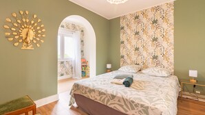 A bedroom with a bed, a nightstand, a lamp, a wall art piece, and a window.