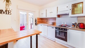 A modern kitchen with white cabinets, a wooden countertop, a stove, and a coffee maker.