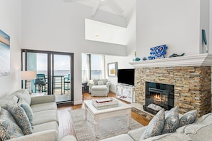 A spacious living area with a fireplace, a balcony with a view, and a cozy seating arrangement.