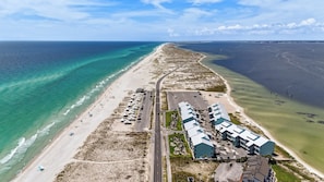 An aerial view of a coastal hotel with a beach, parking area, and ocean views.