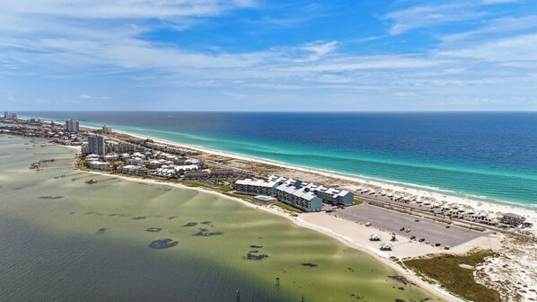 Vista aérea de un hotel costero con varias construcciones, una playa y un puerto deportivo.