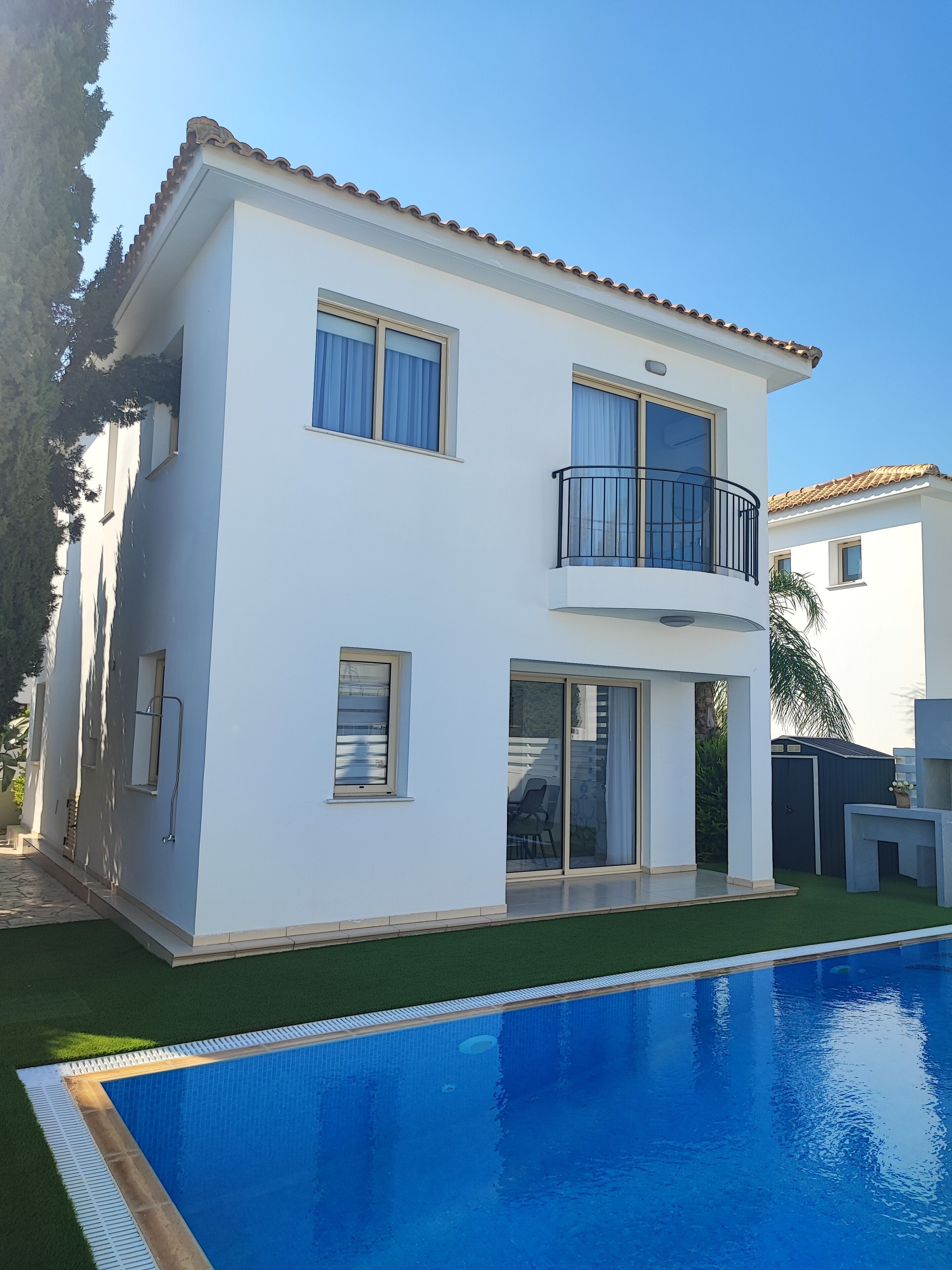 A two-story house with a balcony, a swimming pool, and a garden.