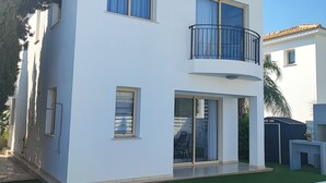 Una casa de dos pisos con balcón, piscina y jardín.