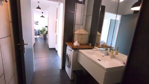 A modern bathroom with a large mirror, a sink, and a washing machine. - Elegant 70m2 Rooftop at the foot of Le Bourget station (Le Bourget)