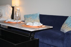 A dining area with a table set for two, featuring a wine glass, plates, and cutlery.