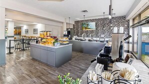 Una cocina moderna con una isla central, taburetes de bar y una barra desayunadora.