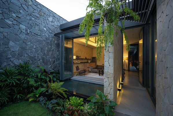 A modern house with a stone exterior, a glass door leading to a living area, and a small pool.