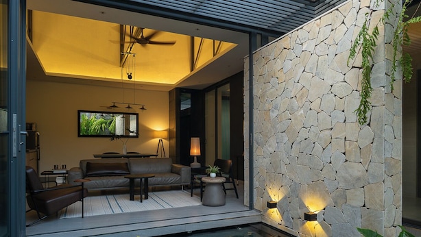 A modern outdoor living area with a stone wall, a pool, and various plants.