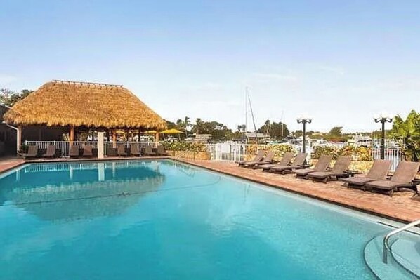 A swimming pool with lounge chairs and a thatched-roof structure.