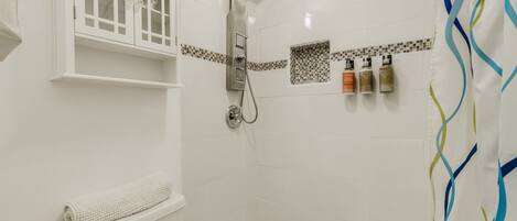 A shower with a glass enclosure, a toilet, and a towel rack.