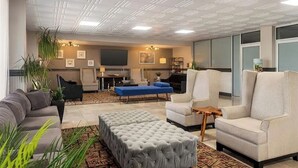 Un salon moderne avec un canapé, un pouf et des fauteuils, un téléviseur à écran plat et une cheminée.