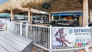 Un espace bar extérieur doté de toits de chaume et de tables en bois.
