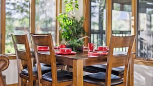 A wooden dining table with six chairs, a potted plant, and red tableware. - Country Club (Flagstaff)