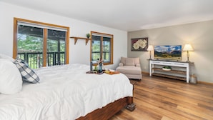 A bedroom with a large bed, a sofa, a console table with a lamp, and a painting on the wall. - Country Club (Flagstaff)