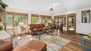 A spacious living room with a leather sofa, a coffee table, and a dining area with wooden chairs and a table. - Country Club (Flagstaff)