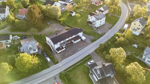 An aerial view of a residential area with houses, a road, and a large building with a flat roof.