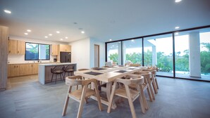 A modern kitchen with wooden cabinets, a central island, and a dining area with wooden chairs.