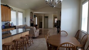 Una cocina amplia con una isla central, taburetes de bar de madera y un comedor con mesa y sillas de madera.