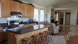 Una cocina moderna con armarios de madera, una isla grande con taburetes y un comedor con sofá y sillas.