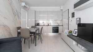 A modern kitchen with a built-in oven and a dining area with a table and chairs. - Italianway Comfort - Fara 29 (Milan)