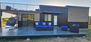 En moderne udendørs terrasse med siddepladser og en hængestol, med udsigt over et smukt landskab.