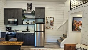 A modern kitchen with dark cabinets, stainless steel appliances, and a wooden dining table. - Gray Haven Near Zion 
& Bryce  (Glendale)