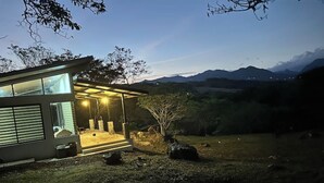 A modern house with a covered porch, large windows, and a view of mountains in the background. - Cabana Vergara Santa Fe (Provincia de Veraguas, Panama)