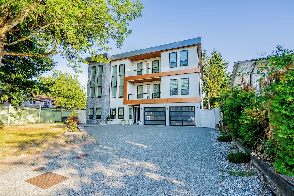 A modern two-story house with a garage, a driveway, and a well-maintained garden.