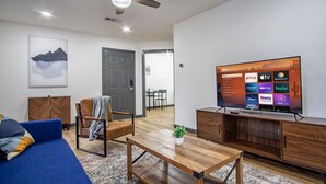 Un salon moderne comprenant un canapé, une table basse, un téléviseur et un ventilateur de plafond.