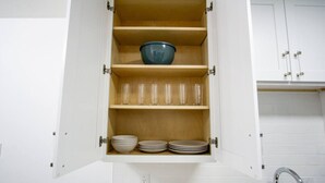 Un meuble de cuisine doté d’étagères où sont rangés des bols, des assiettes et des verres.
