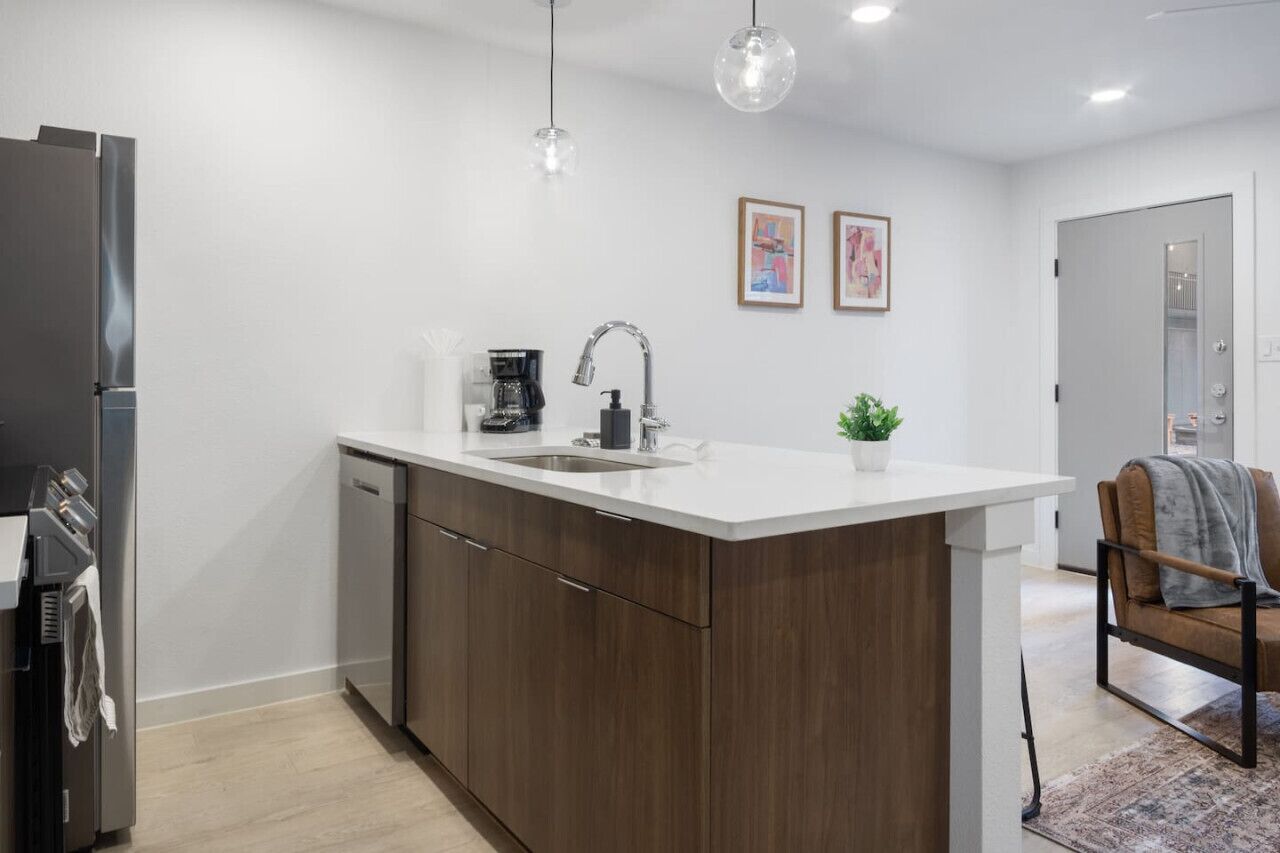 A modern kitchen with a central island, stainless steel appliances, and a coffee maker.
