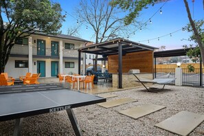 An outdoor seating area with a ping pong table, orange chairs, and a covered seating area. - Immaculate Apartment in Austin 5 Min to Downtown ATX (Austin)