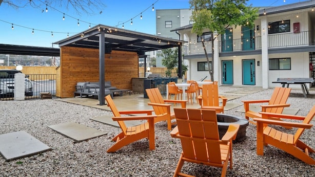 An outdoor seating area with orange chairs and a fire pit, surrounded by a gravel patio. - Immaculate Apartment in Austin 5 Min to Downtown ATX (Austin)