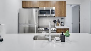 A modern kitchen with stainless steel appliances, a white countertop, and wooden cabinets. - Immaculate Apartment in Austin 5 Min to Downtown ATX (Austin)