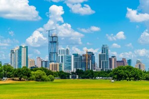 A city skyline with modern high-rise buildings, a construction crane, and a green park area in the foreground. - Immaculate Apartment in Austin 5 Min to Downtown ATX (Austin)