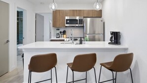 Una cocina moderna con una isla central, electrodomésticos de acero inoxidable y taburetes marrones.
