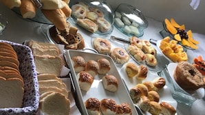 Un buffet proposant une variété de produits de boulangerie, notamment du pain, des viennoiseries et des muffins.
